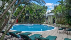 pool at the las americas hotel in guatemala with green lounge chairs around it and a large tree above it