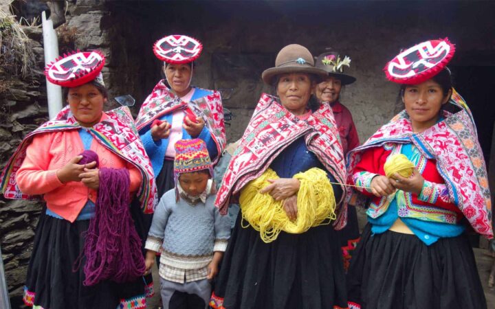 group of mayan women and a young child in peru with brightly colored garments