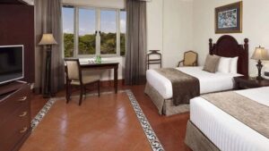 double room with table and chairs, orange floor and large picture window at melia hotel panama canal