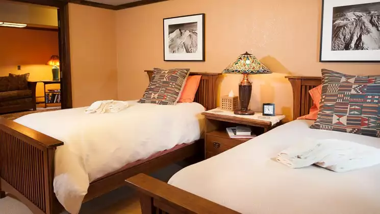 A room with two full beds, a nightstand, and reading lamp with artwork at the Parkside Guest House, a bed and breakfast in Anchorage Alaska