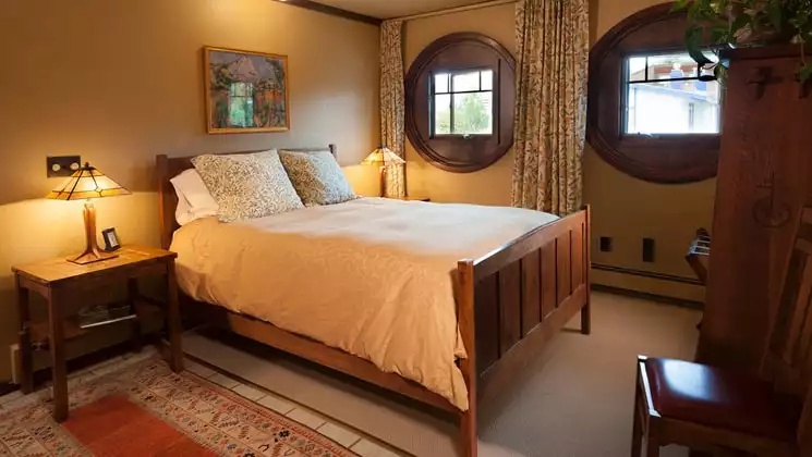 A room with one full bed, two windows, a reading lamp, and nightstand at the Parkside Guest House, a bed and breakfast in Anchorage Alaska