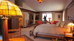 A woman draws the curtains inside a guest room with a large bed and reading lamp at the Parkside Guest House, a bed and breakfast in Anchorage Alaska