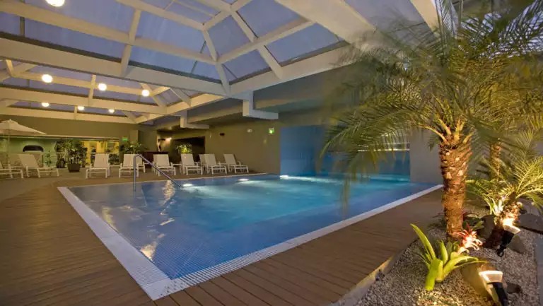 The indoor pool at Casa Andina Private Collection Miraflores, with lounge chairs and a palm tree, is a respite for guests traveling in Peru.