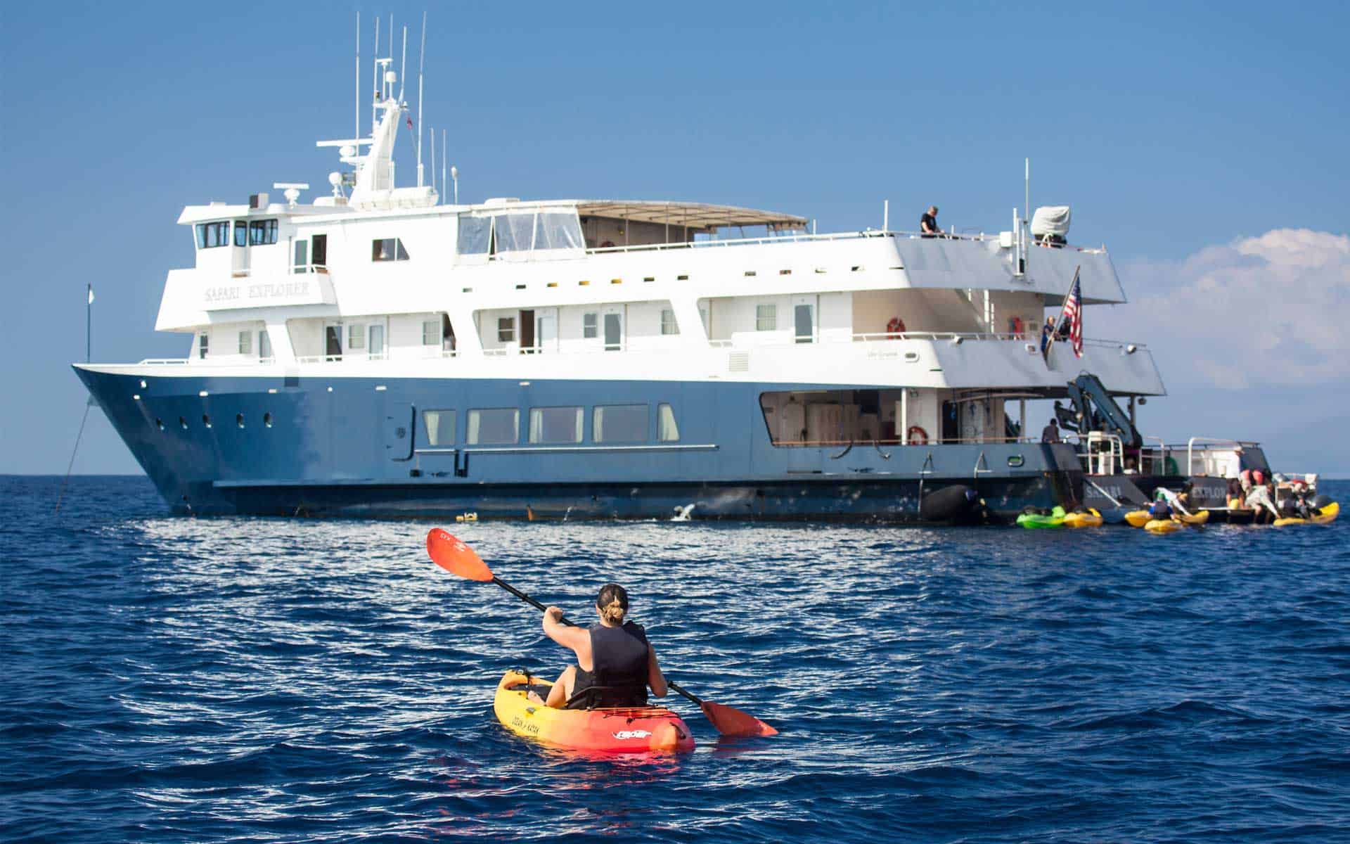 uncruise safari explorer small ship on a sunny day with a kayaker in front of it