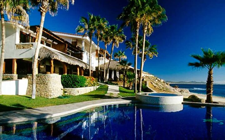 The Cabo Surf Hotel is a boutique beach resort with white stucco walls, surrounded by palm trees, with ocean views in Costa Rica