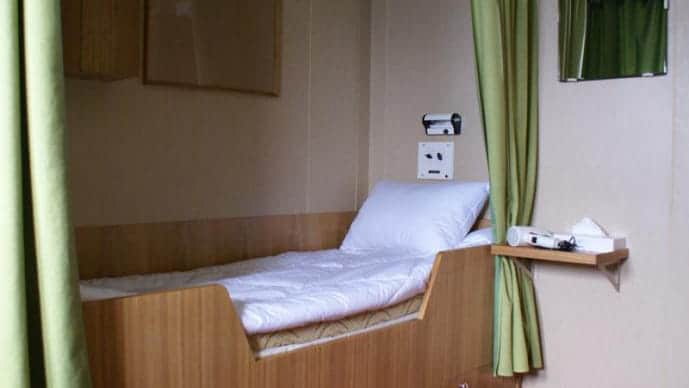 50 Years of Victory stateroom with a single twin, shelf and mirror.