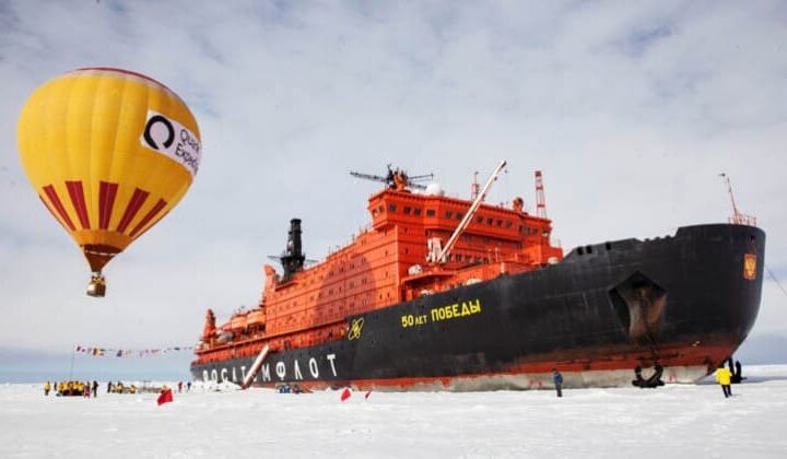 50 Years of Victory anchored along the ice shelf with a hot air balloon, passengers and crew meandering about on the ice.