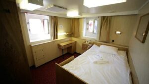 50 Years of Victory, Victory Suite with small bed, desk, nightstand and 2 large windows.