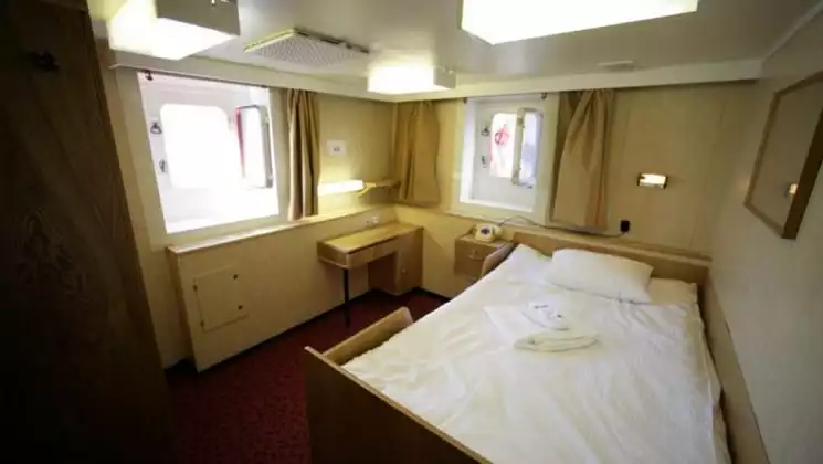 50 Years of Victory, Victory Suite with small bed, desk, nightstand and 2 large windows.