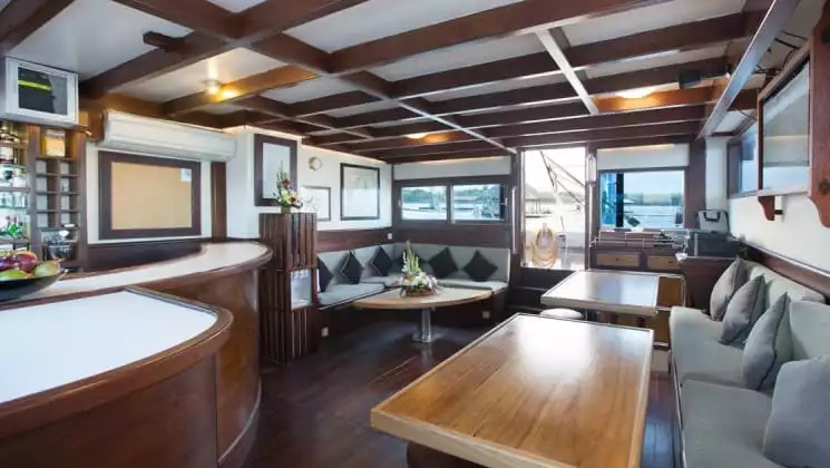Salon on Katharina sailing ship, with wooden tables, plush seating lining the walls & wooden beams.