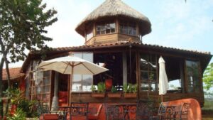 One of the private bungalows at the Cala Mia Boutique Hotel with a thatched roof, outdoor "rancho" patio, hammocks, umbrellas, and handcrafted furniture
