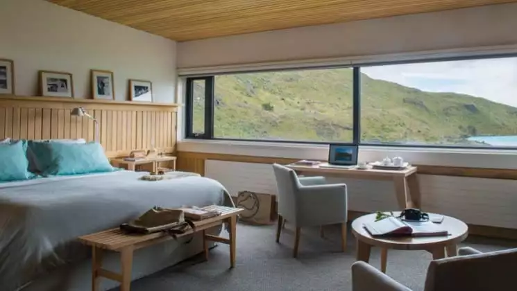 Large bed, writing desk, small table and two chairs in Exploradores Suite looking out to Lake Pehoe at Explora Torres del Paine Lodge in Chile
