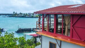 Woman stands on balcony outside her oceanfront suite at Galapagos Habitat Eco Luxury Hotel on Santa Cruz in the Galapagos Islands