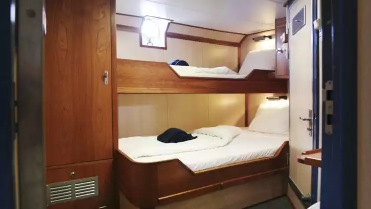 twin beds with a porthole on the wall in the cabin of the Rembrandt van Rijn arctic small ship