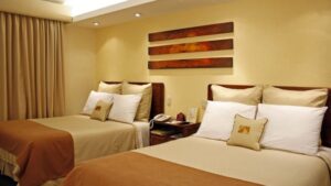 Another angle on a room with two twin beds, artwork, and beige linens at Sonesta Posada del Inca Lake Titicaca, a traditional retreat in the andes