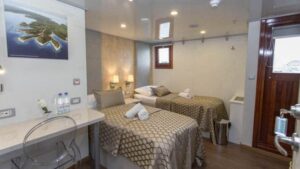 VIP Upper Deck cabin aboard Mediterranean small ship Adriatic Sun, with two twin beds, desk, window and outward-facing door.