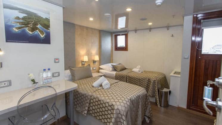 VIP Upper Deck cabin aboard Mediterranean small ship Adriatic Sun, with two twin beds, desk, window and outward-facing door.