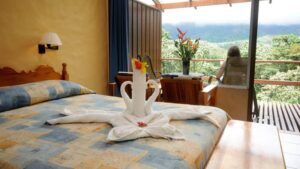 Smithsonian Room with one bed and guest sitting on private deck at Arenal Observatory Lodge in Costa Rica