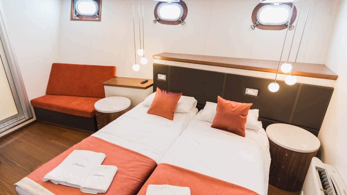 Lower Deck Cabin with 3 portholes, couch, and bed aboard Avangard.