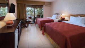 Two large beds made in a spacious room next to door to the outside at Camino Real Tikal Hotel in Guatemala