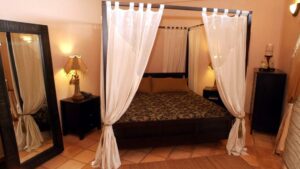 Canopy bed and large mirror in bedroom of Chabil Mar Villas in Belize