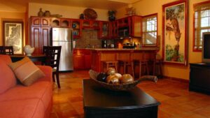 Living room area with couch and coffee table, with kitchen and dining table behind, at Chabil Mar Villas in Belize