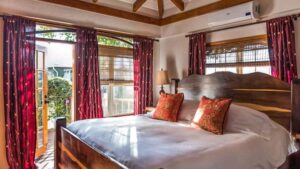 Villa bedroom with wooden bed and headboard and walkout deck at Chabil Mar Villas in Belize