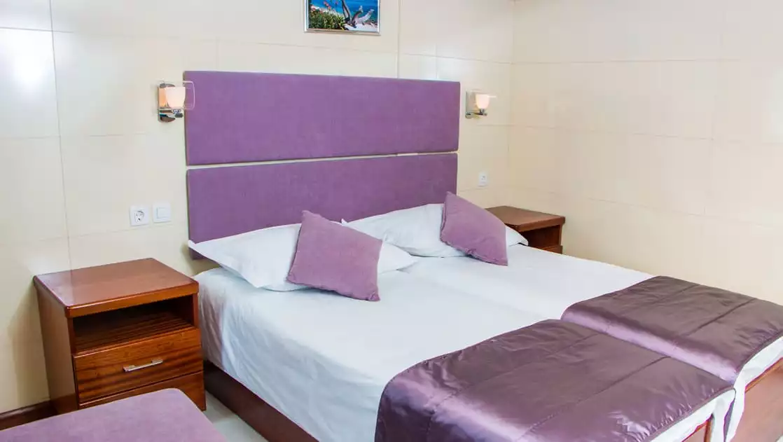 Small ship cruise Futura lower deck cabin with double bed, nightstands, night lights and seat.