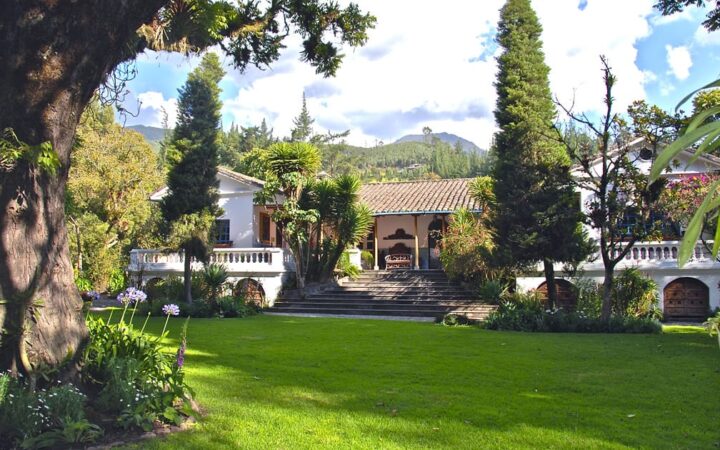Exterior of Hacienda Cusin in Ecuador, with large lawn and local flora
