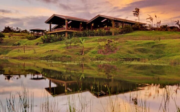 The Arenal Manoa Lodge is situated above the natural hot springs, with its reflection in the water at sunset.