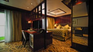 Island Sky Owner's suite with separate living area, desk, queen bed and sliding glass door out to balcony.