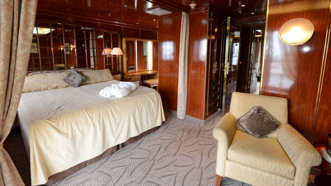 Island Sky Penthouse suite with queen bed, chair, closet, nightstand, reading lights and sliding glass door to balcony.