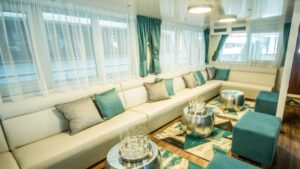 Markan lounge area with banquette couch seating, small coffee tables, ottomans and large windows.
