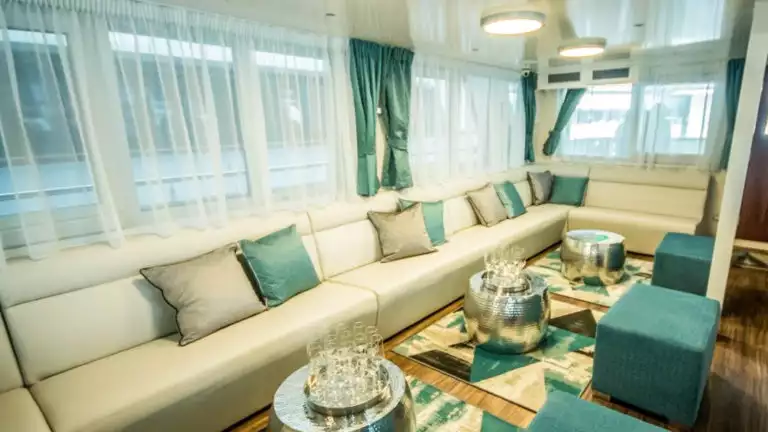 Markan lounge area with banquette couch seating, small coffee tables, ottomans and large windows.