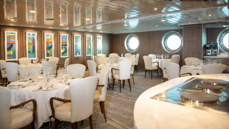 Large dining area with bar and white chairs aboard La Pinta Galapagos.
