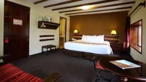 A room with one queen-sized bed, wooden beams, and a warmly decorated interior at the Casa Andina Classic Cusco San Blas, in Cusco, Peru