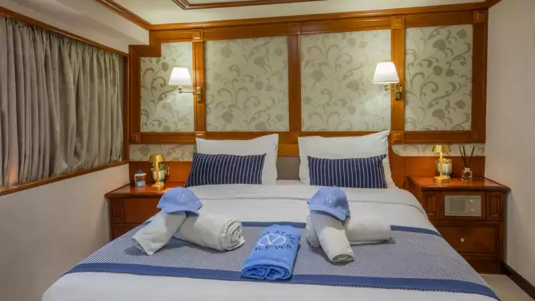Category P cabin aboard Callisto yacht showing a double bed in the center of the cabin with a window to the right