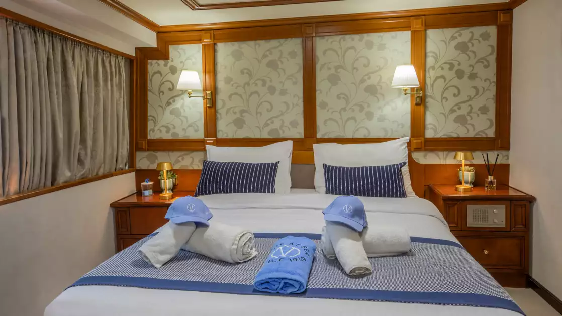 Category P cabin aboard Callisto yacht showing a double bed in the center of the cabin with a window to the right