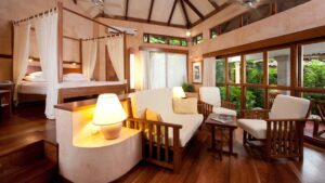 A suite with a queen-sized bed, canopy, and sitting area, in the modern, beachfront Hotel Capitán Suizo at Playa Tamarindo, Costa Rica