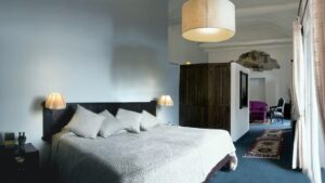 A room at Casa Andina Premium, a hotel in Cusco, Peru, wiith a king-sized beds, fresh linens, large armoire, and long curtains.