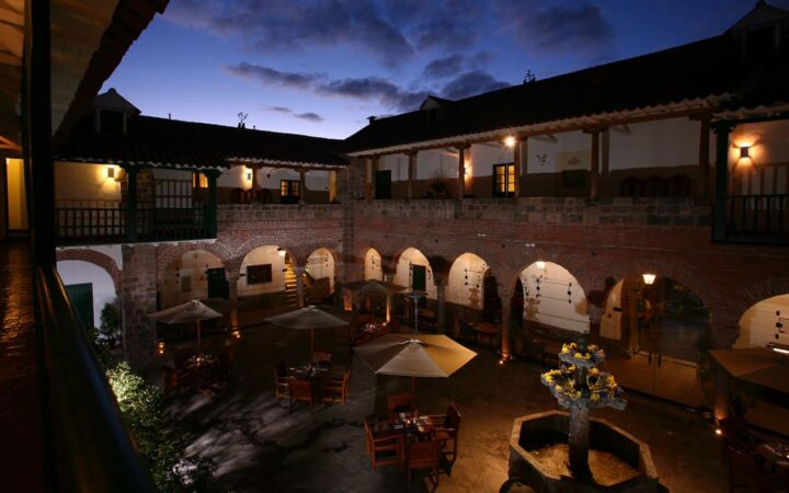 Lights are flickering in the courtyard at Casa Andina Premium in Cusco, Peru, which feels like a rustic Andean home with arches and fountains.