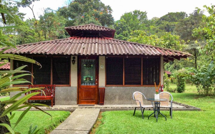 A small palapa building in the jungle of Costa Rica with chairs out front.
