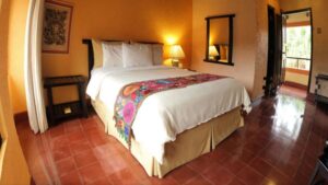 room at clarion copan hotel guatemala with a king bed, tile floors and a mirror on the wall