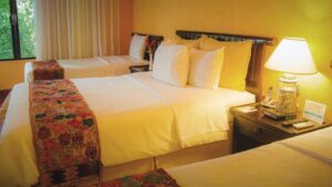 room at clarion copan hotel guatemala with three beds with white linens lined up and a dim light illuminating them