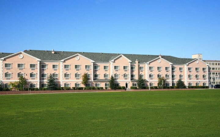 Exterior of Clarion Suites, with large green lawn and blue skies in Anchorage