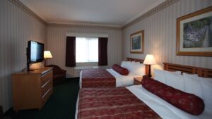 Double room with two beds, dresser, nightstand, reading light and TV at Clarion Suites in Anchorage