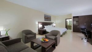 suite room at the clarion victoria panama hotel with a large bed, table and chairs and entry into a bathroom on the far side