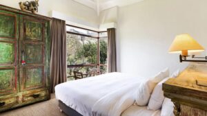 Bedroom with hand-painted wooden furniture and airy balcony with epic views at Colca Lodge in southern Peru