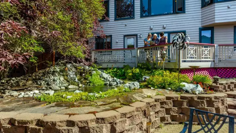 small garden with planted flowers and blooming bushes outside of a small hotel
