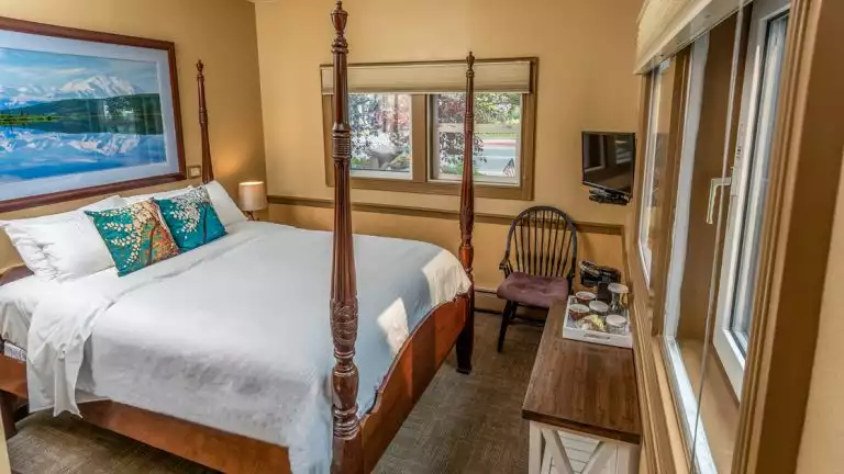 king bed in a hotel room with a large wooden bed with white sheets.